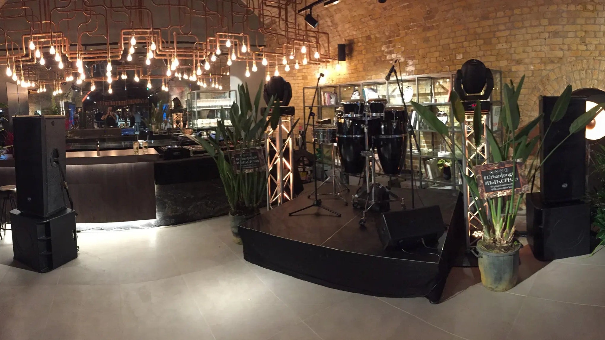 Przestrzeń wydarzeń z sceną, wyposażeniem i dekoracjami w pomieszczeniu z ceglastymi ścianami.