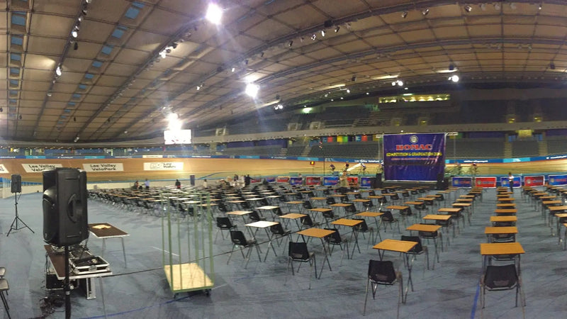 Duża hala sportowa wewnątrz budynku z rzędami krzeseł i sceną, prawdopodobnie przygotowana na wydarzenie.