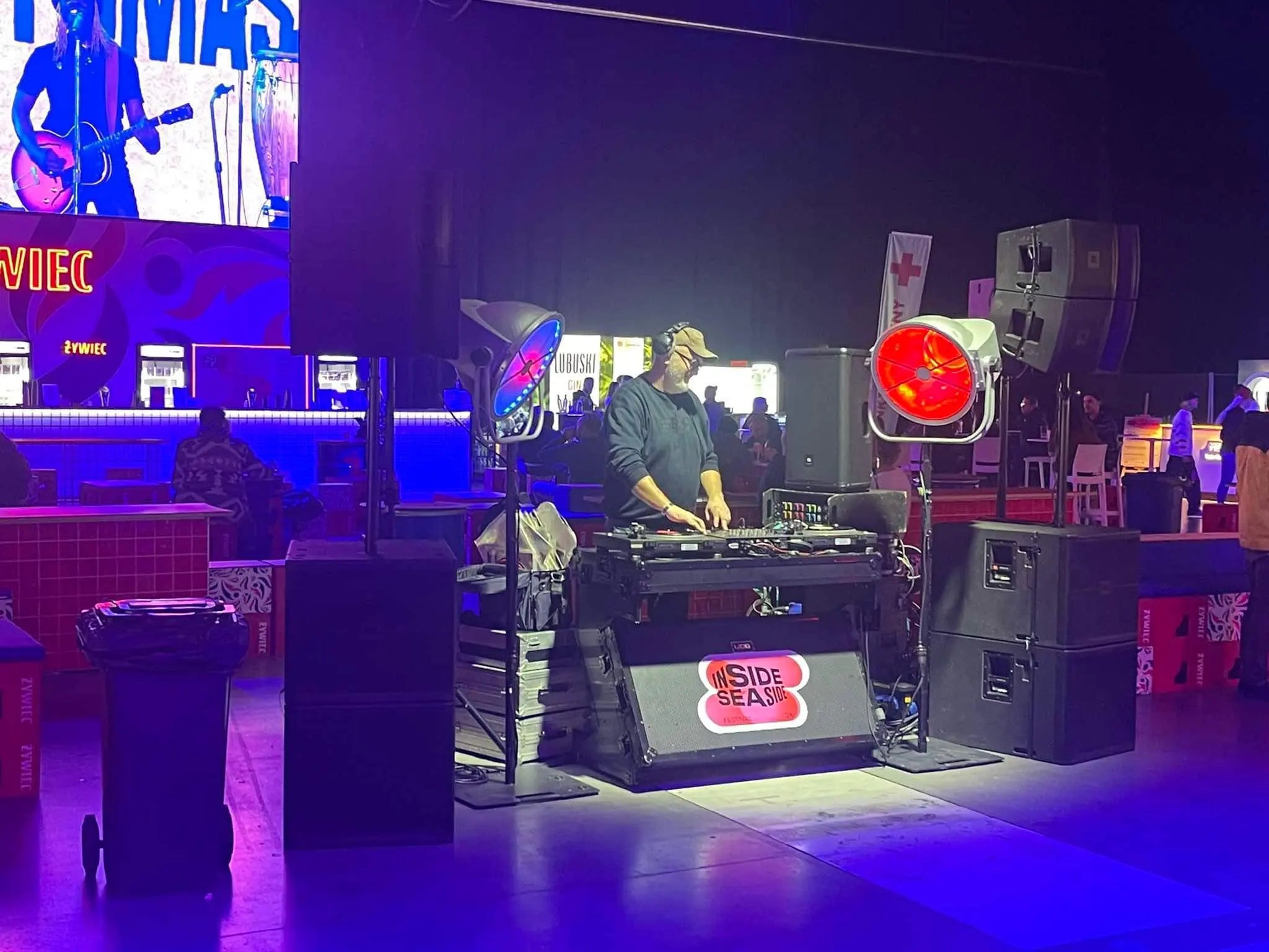 DJ przy stanowisku gramofonowym w klubie nocnym z kolorowymi światłami i sprzętem.